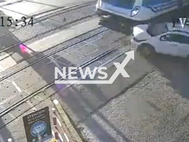 A car is being hit by a train in Quilmes, Argentina, on Tuesday, June 13, 2023.  A woman barely escaped being hit when her car stopped in the middle of the train tracks. Note: Picture is a screenshot from a video (Ministerio de Transporte Argentina/Newsflash)