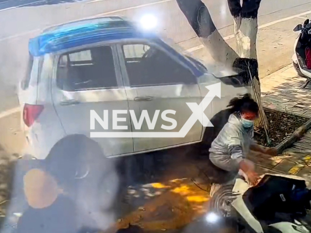 Vehicle nearly hits woman sitting and looking at phone in Baoshan, China, on 22nd March 2022. Note: Picture is a screenshot from a video (1049945429/AsiaWire)