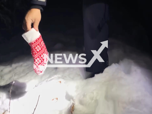 Police officer picks up a mitten, in Ravensburg, Germany, undated. Police searched  for St. Nicholas in a snowy fores.  Note: This picture is a screenshot from the video. (Ravensburg Police/Clipzilla)