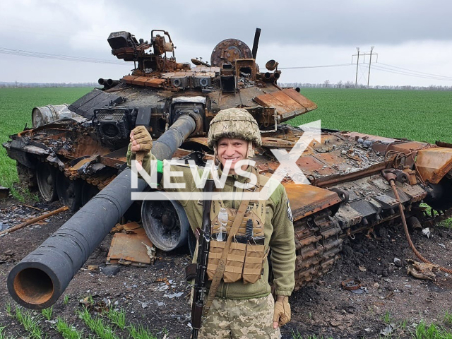 Soldier posing in front of the destroyed T-90 tank 'Vladimir' in Ukraine. Note: Image from soldier of 128 brigade. (@slavik.galas/Newsflash)