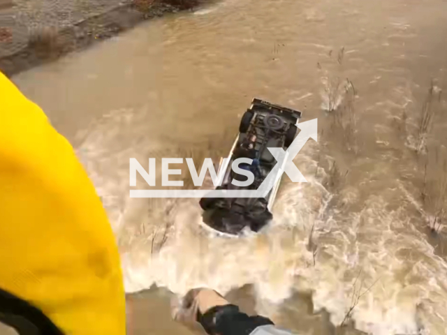 Rescuers rescue a victim of an accident siting on an overturned vehicle in the middle of a creek at Lake Del Valle, in Alameda County, California, USA, on Tuesday, Jan. 23, 2024. Note: Picture is a screenshot from the video. (Golden Gate Division Air Operations/Clipzilla)