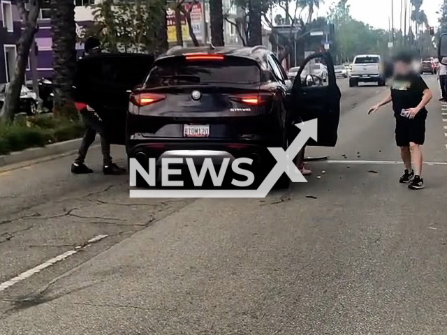 Suspects gathering their belongings from the car before fleeing the scene on foot in Los Angeles, California, USA. Note: This picture is a screenshot from the video (Los Angeles Police Department/Newsflash)