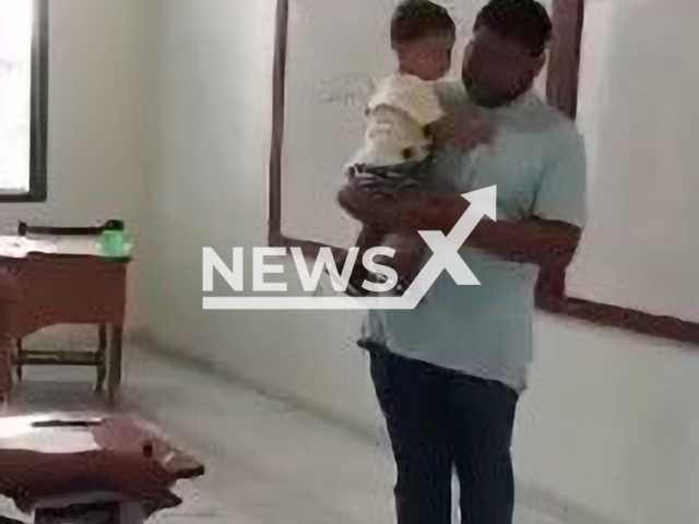 Teacher holds student's son so she can take a test in Jordao, Brazil, undated. The teacher reportedly said that the student never gave up on her studies.Note: Picture is screenshot from a video. (Newsflash)