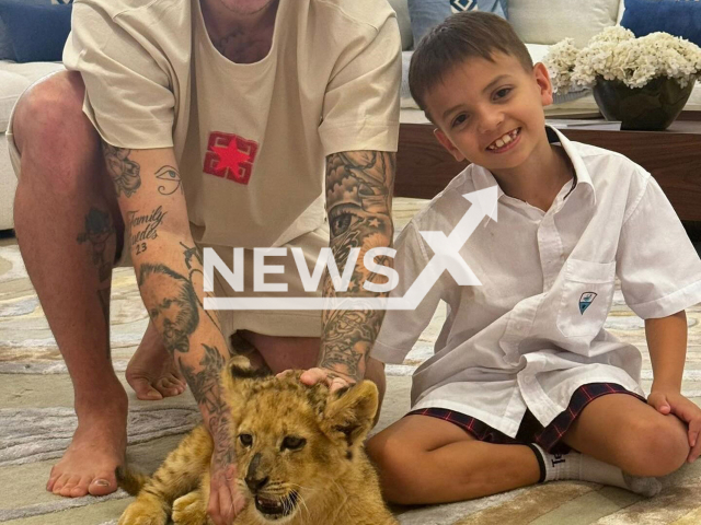 Roger Guedes poses with son and a lion in undated photo. The player has played for Al-Rayyan, from Qatar. Note: Private photo taken from social media. (@rogerguedes23/Newsflash)