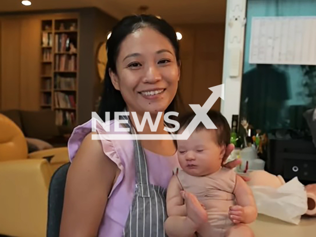 Andrea Lee poses with one of her “babies”, undated. She paints and then sells baby dolls in Singapore. Note: Image is a screenshot from video. (Newsflash)