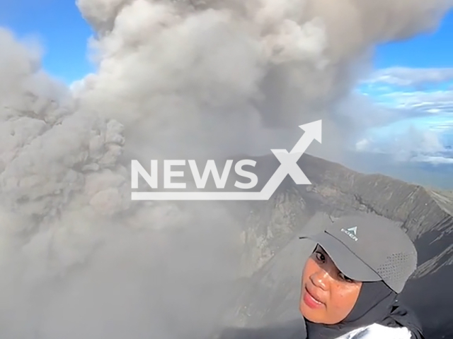 Picture shows female climber still at the peak when the eruption occurred on Mount Dukono, Indonesia, undated. The situation was also recorded as climbers ran down. Note: Image is a screenshot from video. (@nurlitahmd/Newsflash)