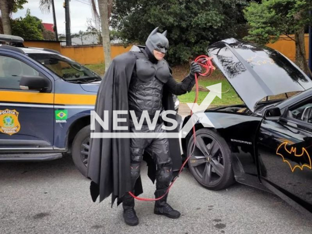 Renato Bilbao, a 54-year-old retiree who incorporates the superhero in volunteer work, charges the battery of the  Batmobile ended up failing, in May, 2022, in Biguacu, Brazil. Note: Police photo. (PRF/Newsflash)