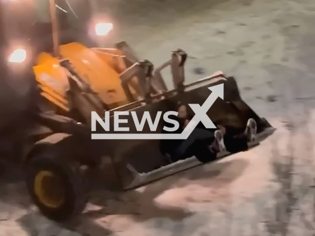 This image is a screen grab of the video supplied titled NewsX-TractorJoyriding-01.mp4: Two women ride a tractor along the road; one sleeps as the driver lifts and lowers the bucket, then a man arrives to help move the sleeping woman at night in the Ozero Dolgoe park in Saint Petersburg, Russia, undated. The video was shared on the telegram channel on Saturday, Feb. 22, 2025. (Clipzilla/NX)