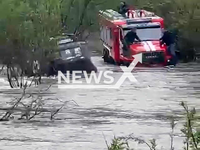 This image is a screen grab of the video supplied titled NewsX-FloodCar-01.mp4: Footage shows firefighters attempting to rescue a driver trapped in a flooded car but the powerful current thwarts their efforts, highlighting the severity of the regional flooding in a river in the Lesozavodsky District, Primorsky Krai, Russia on Saturday, May 3, 2025.(Clipzilla/NX)