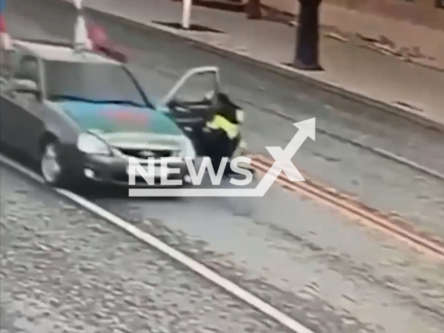 This image is a screen grab of the video supplied titled NewsX-RecklessDrag-01.mp4: CCTV footage captures the moment a reckless driver attempted to flee a traffic stop by speeding off with a police officer clinging to the car door in Tyumen, Russia on Friday, May 9, 2025.(Clipzilla/NX)