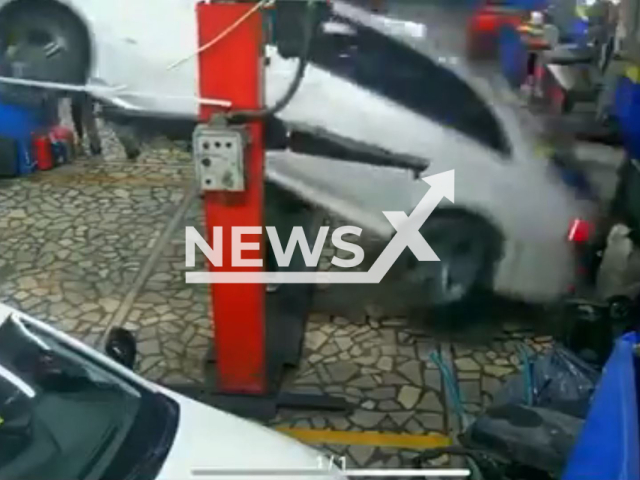 This image is a screen grab of the video supplied titled NewsX-MechanicCar-01.mp4: CCTV footage shows a car unexpectedly overturning and falling on the Fatih Tastan 43 at an auto repair shop in Beykoz, Istanbul Province, Turkey on the 10th of April, 2025.(Clipzilla/NX)