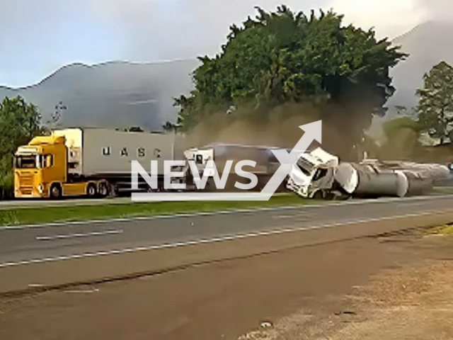 This image is a screen grab of the video supplied titled NewsX-TruWey-01.mp4: CCTV footage shows a slow-moving truck entering the highway is rear-ended by a second truck that attempted to swerve, while a third truck, trying to avoid the pile-up, veers into the central reservation and overturns at the BR-277 highway near Morretes, Brazil on Thursday, May 15, 2025.(Clipzilla/NX)