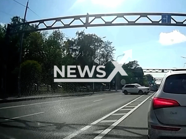 This image is a screen grab of the video supplied titled NewsX-IllegalTurn-01.mp4: Dashcam shows a white Rolls-Royce illegally turning through a safety island and striking a motorcyclist in the left lane, then running him over without stopping at the intersection of Petergofskoe Shosse and Admirala Tributsa Street, St. Petersburg, Russia on Sunday, June 1, 2025.(Clipzilla/NX)