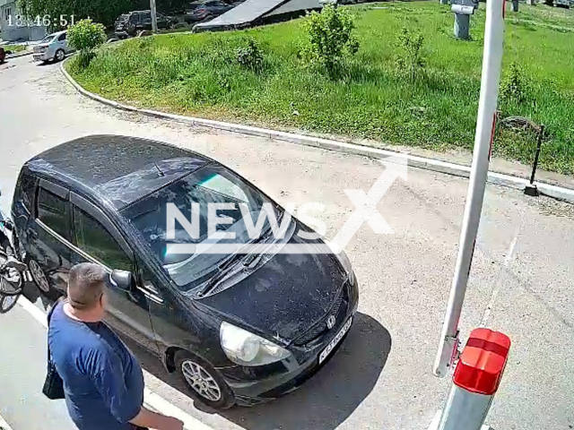 This image is a screen grab of the video supplied titled NewsX-CrashAndDash-01.mp4: CCTV footage shows a cyclist trying to squeeze between a car and a pedestrian, and as a result, she damaged the car in Barnaul, Russia on Thursday, May 22, 2025.(Clipzilla/NX)