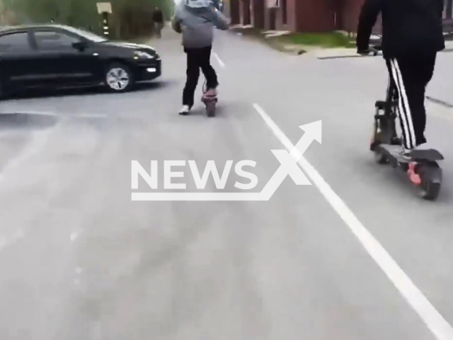 This image is a screen grab of the video supplied titled NewsX-FastRiders-01.mp4: Footage shows two young people on electric scooters crashing into a passing car in Novy Urengoy, Russia on Saturday, June 21, 2025.