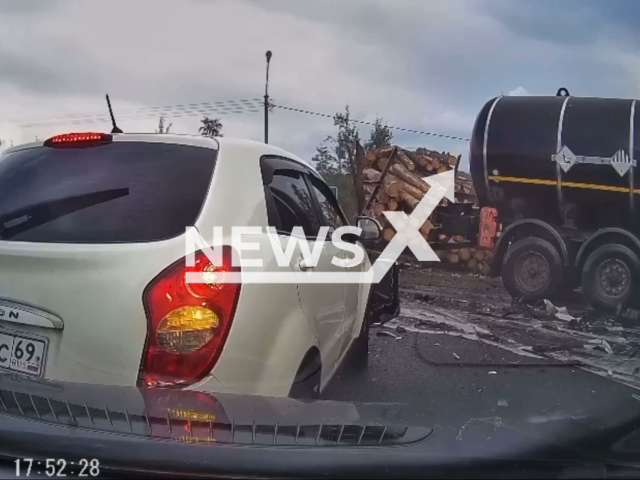 This image is a screen grab of the video supplied titled NewsX-LorriesRoad-01.mp4: Footage shows a truck carrying bitumen failing to brake and crashing into a timber lorry before slamming into a car, after which the couple outside are seen emerging unharmed and embracing on the road beside their wrecked vehicle at Tosnensky District, Leningrad Oblast, Russia on Friday, Aug 1, 2025.(Clipzilla/NX)