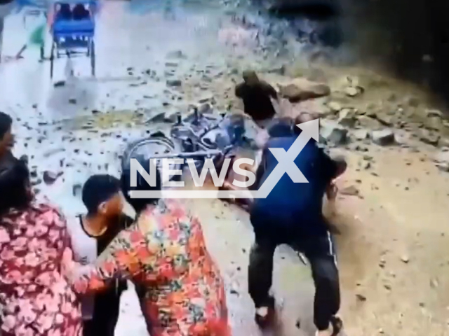 This image is a screen grab of the video supplied titled NewsX-DebrisFall-01.mp4: CCTV shows three local youths riding a motorcycle narrowly escapes as debris fall while passing below a hillside in Har Ki Pauri, Haridwar in the Indian state of Uttarakhand on Tuesday, Aug 5, 2025.( Clipzilla/NX)