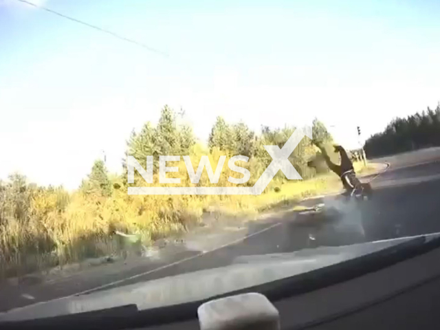 This image is a screen grab of the video supplied titled NewsX-ManBiker-01.mp4: Footage shows a car making a U-turn and causing a biker to crash, with the driver inspecting the damage to his car instead of checking on the biker in Surgutsky District, Khanty-Mansi Autonomous Okrug, Russia on Tuesday, Aug 5, 2025.(Clipzilla/NX)