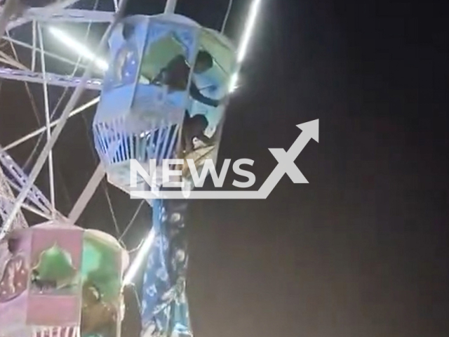 A woman hangs from a giant wheel in Bhatapara, India, undated. A man saved her. Note: Photo is a screenshot from a video. (Newsflash/NX)