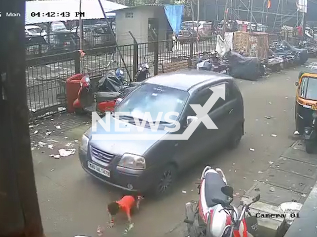 This image is a screen grab of the video supplied titled NewsX-UnderCar-01.mp4: CCTV shows car hitting a child playing on the street in Mumbai, India on Monday, Aug 11, 2025.(Clipzilla/NX)