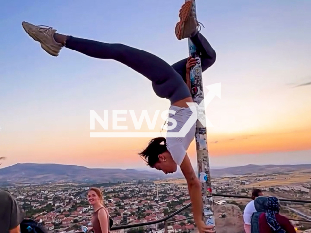A woman dances on a flagpole in Cappadocia, Turkey, undated. The act sparked outrage. Note: Photo is a screenshot from a video. (@blittem/Newsflash/NX)