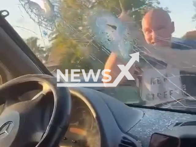 This image is a screen grab of the video supplied titled NewsX-HammerSmash-01.mp4: Footage shows drunk driver smashing minibus windshield with hammer in Omsk, Russia on Aug 25, 2025.(Clipzilla/NX)