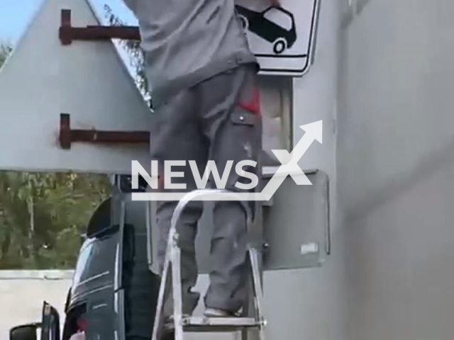 This image is a screen grab of the video supplied titled NewsX-SignPass-01.mp4: Footage shows man bending road sign to allow a truck to pass in Omsk, Russia, undated. Footage shared by Omsk Mayor Sergei Shelest on Wednesday, Sep. 10, 2025.(Clipzilla/NX)