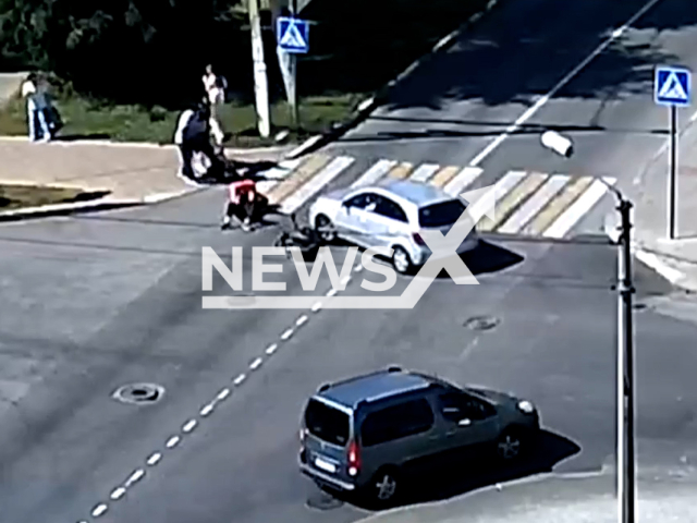 This image is a screen grab of the video supplied titled NewsX-TurningIntersection-01.mp4: CCTV footage shows a car turning as a courier on a moped attempts to overtake, resulting in a side collision at the intersection of Oktyabrskaya Street and Pervomayskaya Street in Belgorod, Russia on on Wednesday, Sep. 10, 2025.