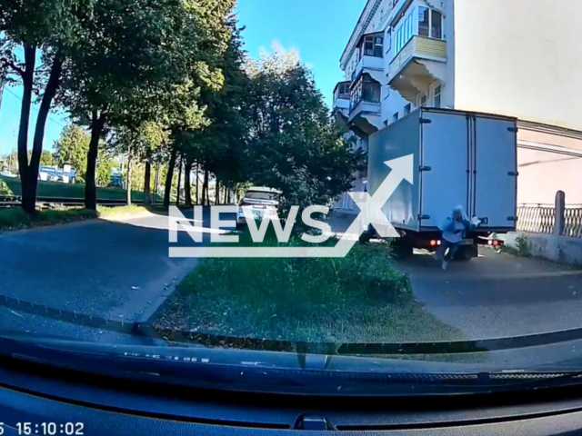 This image is a screen grab of the video supplied titled NewsX-SideWalkWom-01.mp4: Dashcam shows an elderly woman standing on the sidewalk, absorbed in her phone or a document, as a reversing Gazelle truck fails to see her, knocking her down and running over her in Kolomna, Russia on Tuesday, Sep. 16, 2025.(Clipzilla/NX)