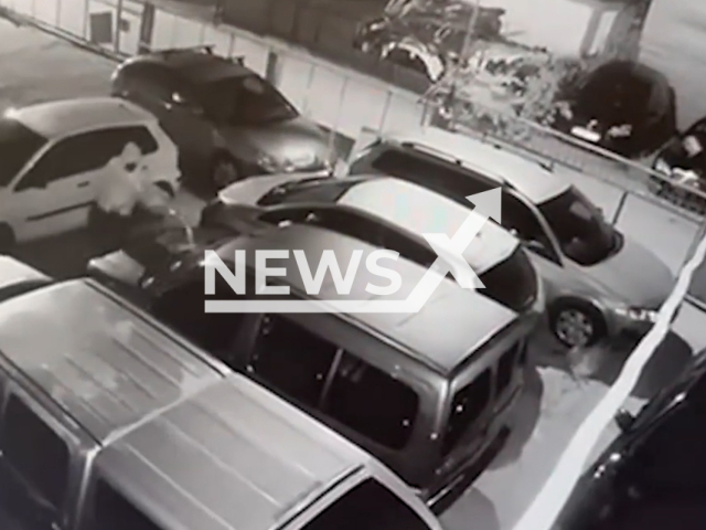This image is a screen grab of the video supplied titled NewsX-VehiclesAblaze-01.mp4: CCTV shows a man jumping over a fence and entering a car service park, dousing the vehicles with flammable material and setting them on fire in Skopje, North Macedonia on Monday, Sep. 15, 2025.(Clipzilla/NX)