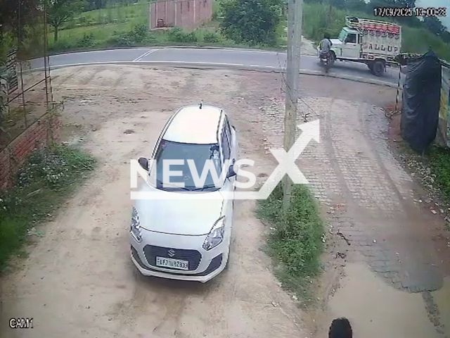 This image is a screen grab of the video supplied titled NewsX-CrossingBike-01.mp4: Footage shows a speeding pickup truck slamming into a motorbike that was emerging from a narrow village lane onto the main road in Fatehpur, Uttar Pradesh, India on Wednesday, Sep. 17, 2025.(Clipzilla/NX)
