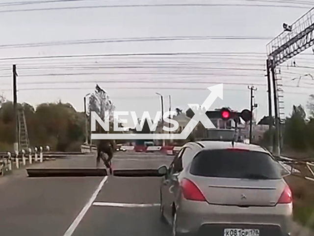 This image is a screen grab of the video supplied titled NewsX-RailwayScooter-01.mp4: Footage shows scooter hitting railway crossing barrier and falling in Leningrad Oblast, Russia on Monday, Sep. 15, 2025.(Clipzilla/NX)