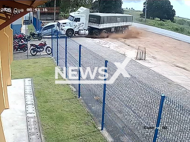 This image is a screen grab of the video supplied titled NewsX-TruckerScools-01.mp4: Security camera footage shows out-of-control truck invading the parking lot of a school and knocking down part of the building's structure in Sao Sebastiao, Alagoas, Brazil on Wednesday, Oct. 1, 2025.(Clipzilla/NX)