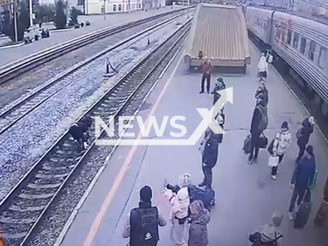 This image is a screen grab of the video supplied titled NewsX-TrackLay-01.mp4: Footage shows a man stumbling on railroad tracks is miraculously untouched as a train passes directly over him in  Tyumen, Russia on Wednesday, Oct. 1, 2025.(NewsX)