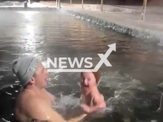 This image is a screen grab of the video supplied titled NewsX-OneIcy-01.mp4: Footage shows a father lowering his son into the icy water in Surgut, Russia on Monday, Jan. 12, 2026.(Clipzilla)