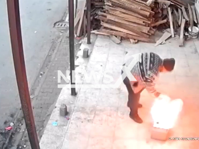 This image is a screen grab of the video supplied titled NewsX-TeaMan01-01.mp4: CCTV shows a man trying to make tea at a workplace pouring gasoline onto a fire, causing a sudden flare-up that engulfs him in flames before he narrowly escapes in Yuregir, Adana Province, Turkey on Wednesday, Jan. 21, 2026.(Clipzilla)