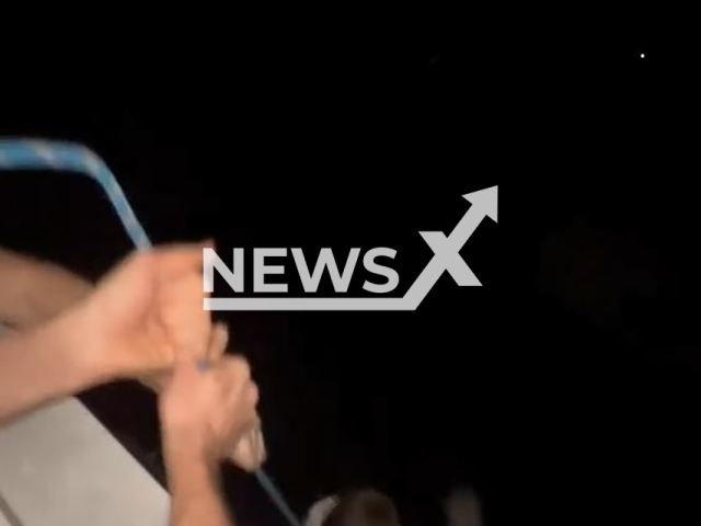 This image is a screen grab of the video supplied titled NewsX-BalconyBoy-01.mp4: Footage shows an intoxicated man with a rope lowering child from a seventh-floor balcony as friends laugh off-camera in Russia. The footage emerged on 28 January 2026.(Clipzilla)
