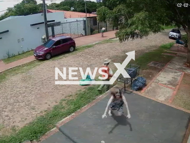 This image is a screen grab of the video supplied titled NewsX-GarbageCollector-01.mp4: CCTV shows a woman tripping while handing trash to a garbage truck, lying ignored on the ground as the crew continues working, before the reversing truck nearly crushes a worker who manages to grab on and escape unharmed in Luque, Paraguay, on Monday, Feb. 2, 2026.(Clipzilla)