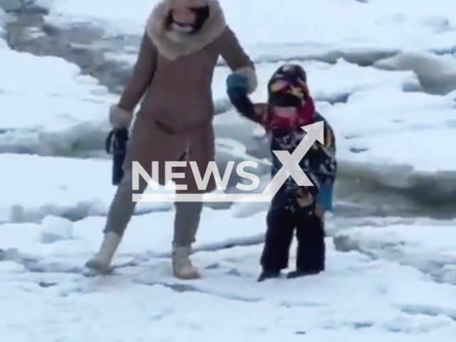 This image is a screen grab of the video supplied titled NewsX-BrokenIce-01.mp4: Footage shows a mother and her young son walking on the barely frozen water after an icebreaker passed by on the river Neva, Saint Petersburg, Russia on Tuesday, Feb. 10, 2026.(Clipzilla)