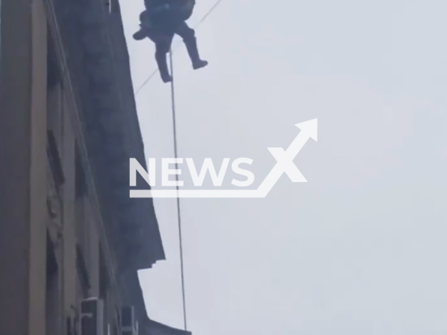 This image is a screen grab of the video supplied titled NewsX-ElectricalCableRescue-01.mp4: Worker hangs from power lines after falling from the roof of a building in St Petersburg, Russia, in footage released on 11 February 2026.(Clipzilla)