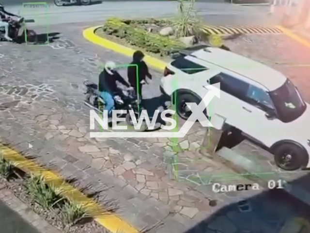 This image is a screen grab of the video supplied titled NewsX-ThwartRobbery-01.mp4: Surveillance footage shows gunmen on a motorcycle attacking a luxury SUV carrying an avocado businessman, with bodyguards returning fire and wounding one suspect before police take him into custody in Uruapan, Michoacan, Mexico on Tuesday, Feb. 10, 2026.(Clipzilla)