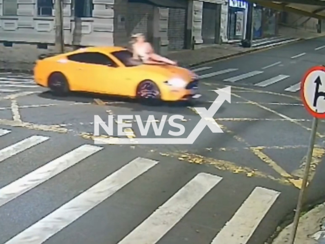 This image is a screen grab of the video supplied titled NewsX-DronesOrekhovo-01.mp4: Man in Mustang runs over ex-girlfriend and carries her on the bonnet through the streets of Ponta Grossa, Brazil, on Sunday, 15 February 2026.(Clipzilla)