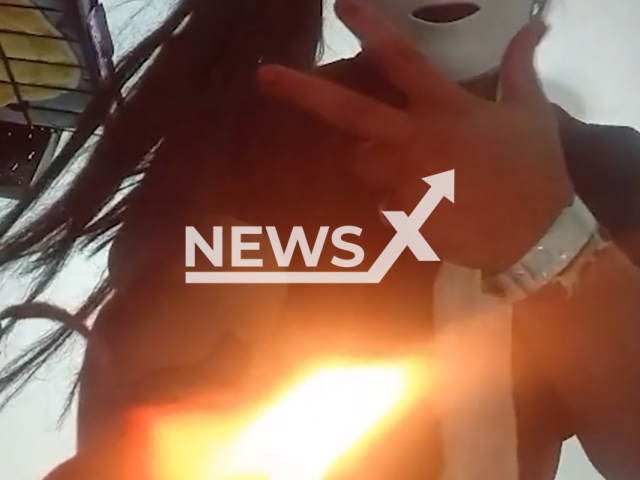 Beatriz Elissandra Marques Carvalho films herself wearing a mask and displaying a lighter to the camera after torturing a man she met in a bar in Ceilandia, Brazil, on 24 February 2026. She later looked for him at a hospital to "finish him off". Note: Photo is a screenshot from the video (Newsflash)
