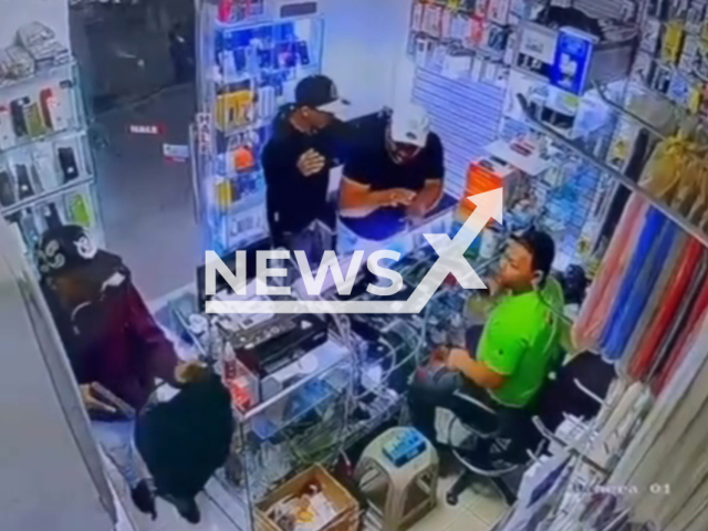 This image is a screen grab of the video supplied titled NewsX-VillaMellaRobbery-01.mp4: Security camera footage captures the moment two armed men stormed a shop to steal mobile phones, before the owner confronted them and opened fire in self-defense, leaving one suspect dead one wounded in Villa Mella, Dominican Republic on Wednesday, Feb. 25, 2026.(Clipzilla)