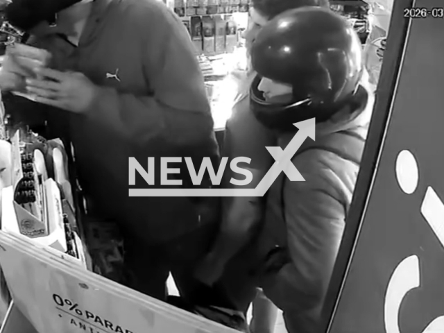 This image is a screen grab of the video supplied titled NewsX-RoberyPho-01.mp4: CCTV shows two motorcycle-borne thieves robbing a kiosk and threatening a customer with a knife pressed to his throat in La Plata, Argentina on Monday, Mar. 2, 2026.(Clipzilla)