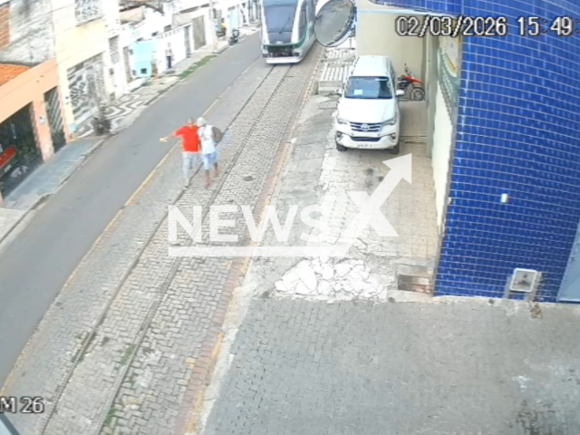 This image is a screen grab of the video supplied titled NewsX-HeirTrein-01.mp4: CCTV footage shows a man sprinting onto a light rail track and pulling a distracted pedestrian to safety moments before an approaching train in Sobral, Ceara, Brazil on Monday, Mar. 2, 2026.(Clipzilla)