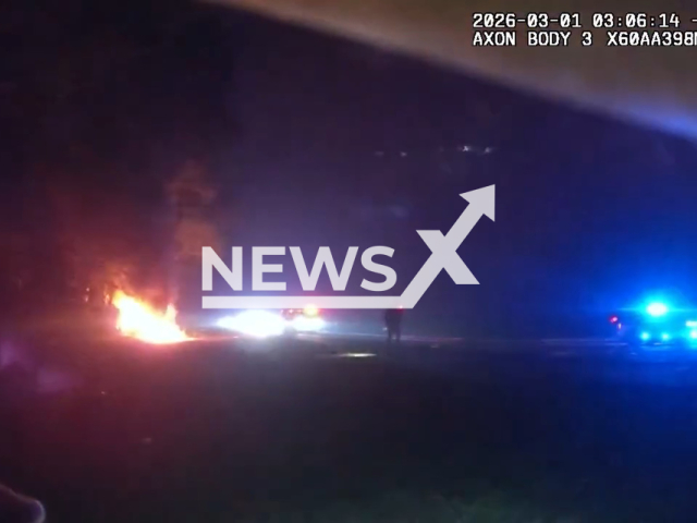 This image is a screen grab of the video supplied titled NewsX-BurningCar-01.mp4: Footage shows deputies pulling an injured driver away from a burning car along after a multi‑vehicle crash left him ejected and unable to move, prompting the rescue to prevent him from being overcome by the flames at I‑95 in St. Johns County, Florida, United States on Sunday, Mar. 1, 2026.