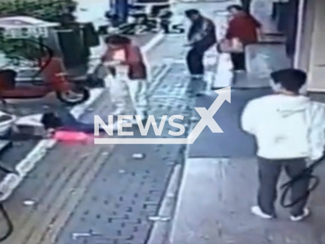 Woman walking on sidewalk hit by a falling object in Jiujiang, China. Note: This picture is a screenshot from the video (AsiaWire).