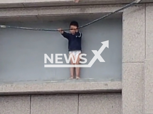 Police and citizens rescue a three-year-old boy clinging tightly to a cable outside a third floor in a residential community in Ganzhou District, Zhangye City, Gansu Province, China on May 6, 2026. Note: Photo is a screenshot from a video. (AsiaWire/NX)