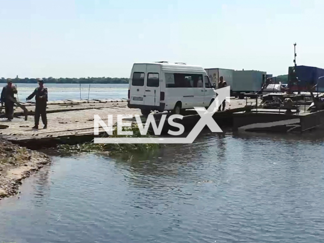 Soldiers of the engineering unit of the Russian Armed Forces help to arrange cars of civil people on a pontoon ferry for crossing the Dnieper River, Kherson region, Ukraine  in an undated photo. Pontoon ferry was organized to ensure the uninterrupted functioning of the transport infrastructure of Kherson region in Ukraine. Note: Picture is a screenshot from a video (@nm_dnr/Newsflash)